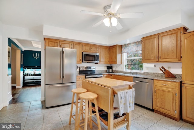 kitchen featuring ceiling fan, appliances with stainless steel finishes, light tile patterned flooring, light stone counters, and sink