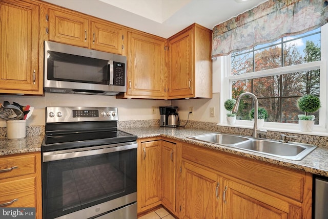 kitchen featuring light tile patterned floors, light stone countertops, sink, and stainless steel appliances