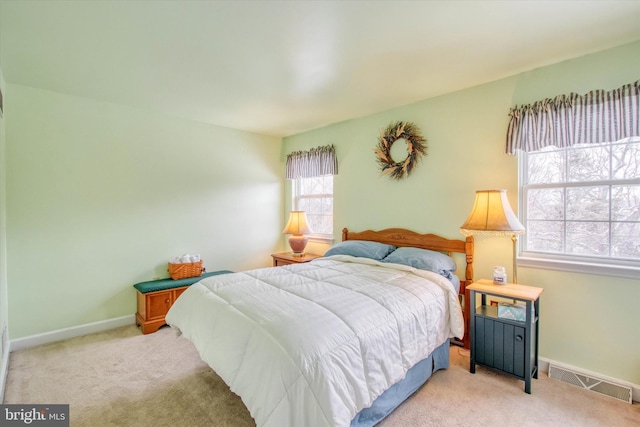 bedroom with light carpet and multiple windows