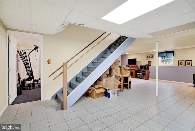 basement with light tile patterned floors and a paneled ceiling