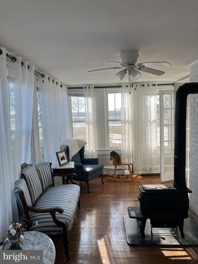 interior space featuring ceiling fan, a wood stove, and hardwood / wood-style floors