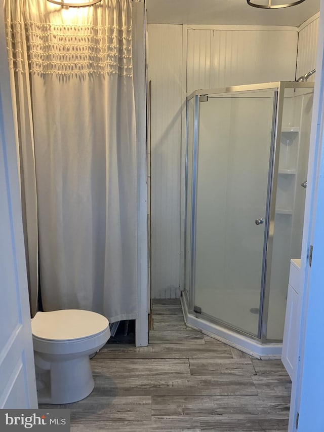 bathroom with a shower with shower door, hardwood / wood-style floors, and toilet