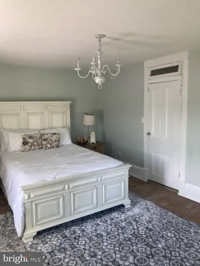 unfurnished bedroom featuring dark wood-type flooring and an inviting chandelier