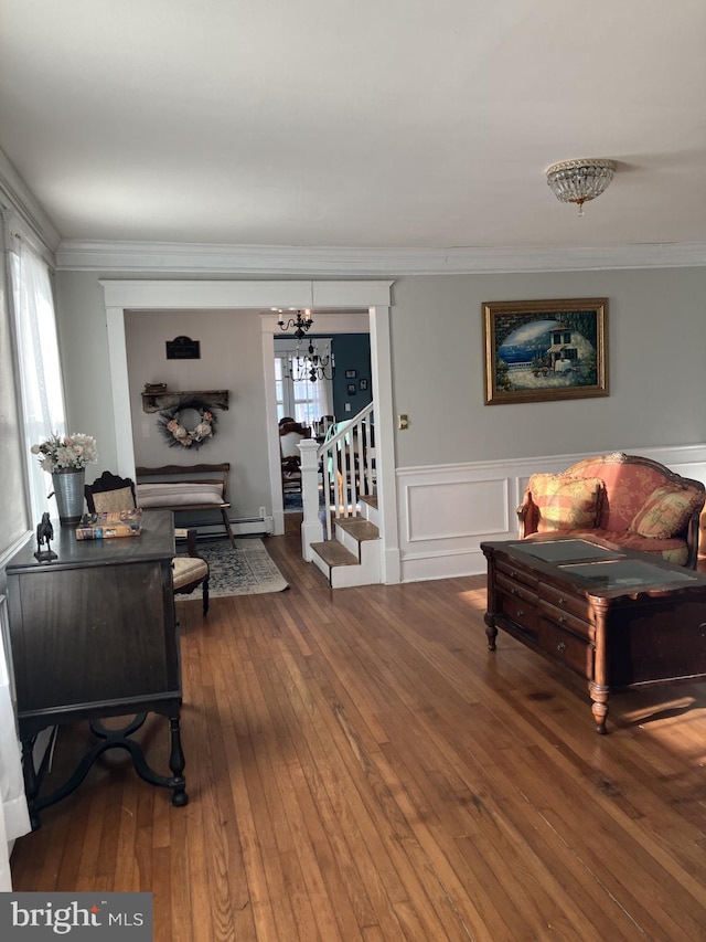 living room with dark wood-type flooring, a baseboard heating unit, and ornamental molding