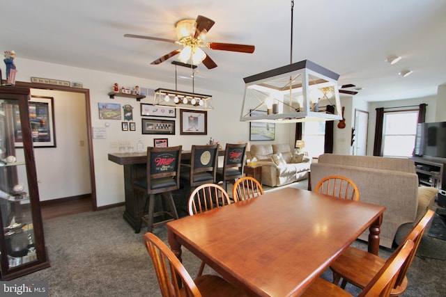 carpeted dining area with ceiling fan with notable chandelier