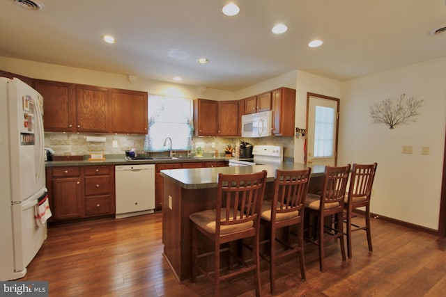 kitchen with dark hardwood / wood-style floors, decorative backsplash, white appliances, and sink