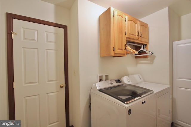 clothes washing area featuring cabinets and washer and clothes dryer