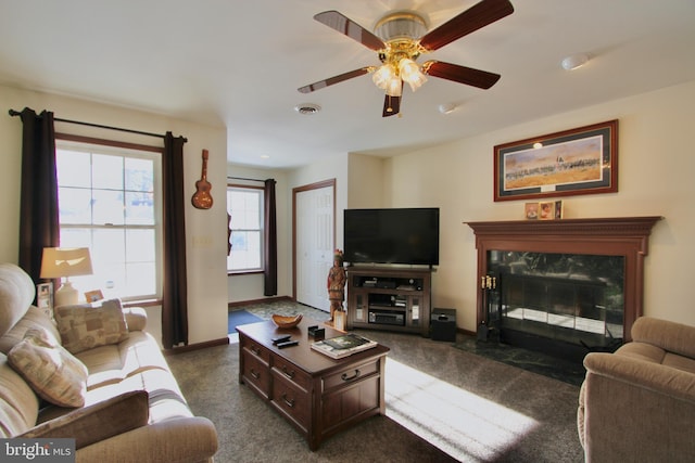 living room with dark colored carpet, ceiling fan, and a premium fireplace