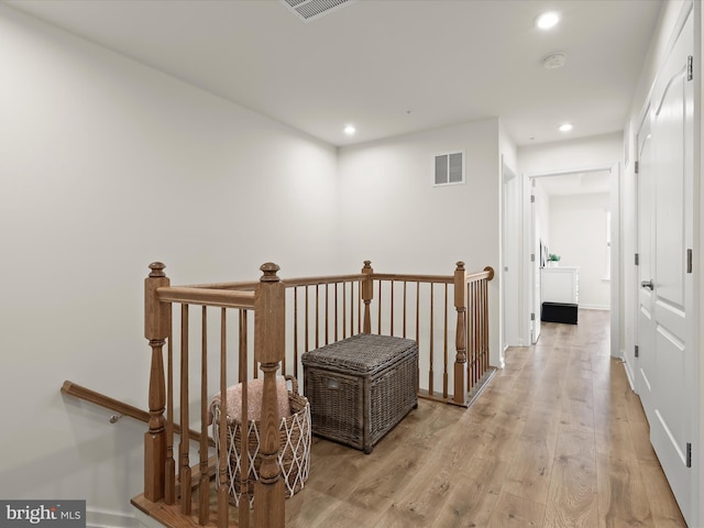 hall featuring an upstairs landing, visible vents, light wood-style flooring, and recessed lighting