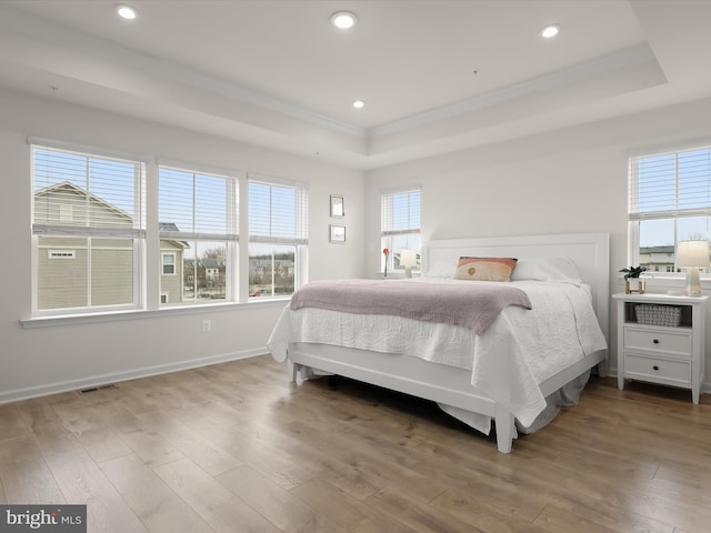 bedroom featuring visible vents, recessed lighting, a raised ceiling, and wood finished floors