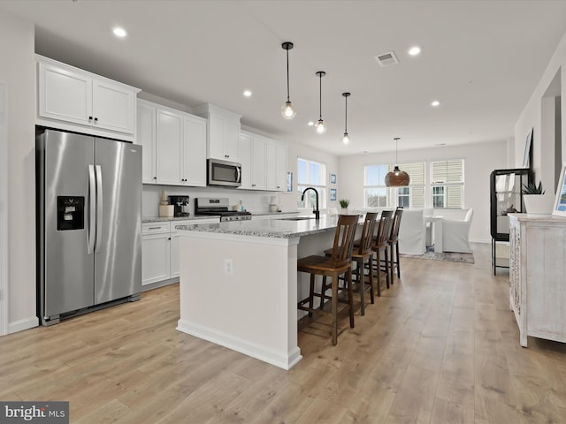 kitchen featuring appliances with stainless steel finishes, white cabinetry, an island with sink, and a sink