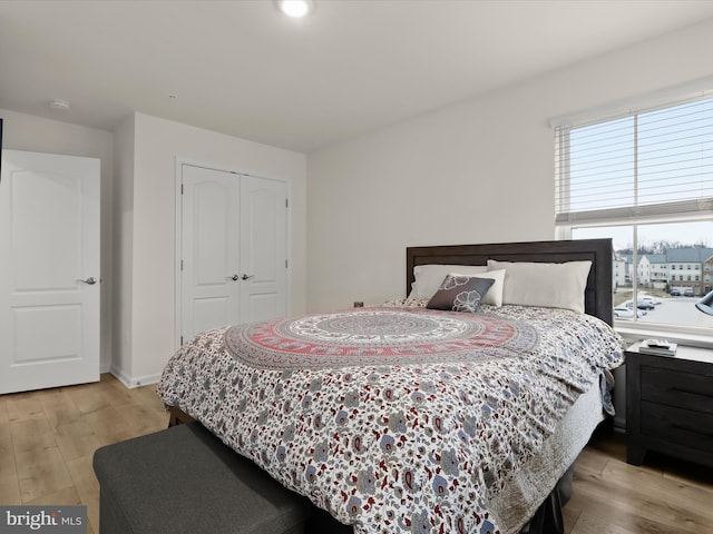 bedroom featuring baseboards, a closet, and light wood finished floors