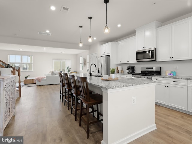 kitchen with light wood-type flooring, stainless steel appliances, and visible vents