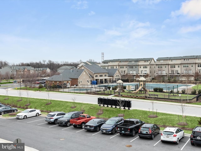 uncovered parking lot featuring a residential view and fence