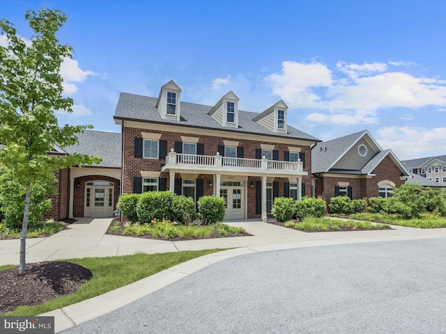 colonial inspired home with french doors, brick siding, and a shingled roof