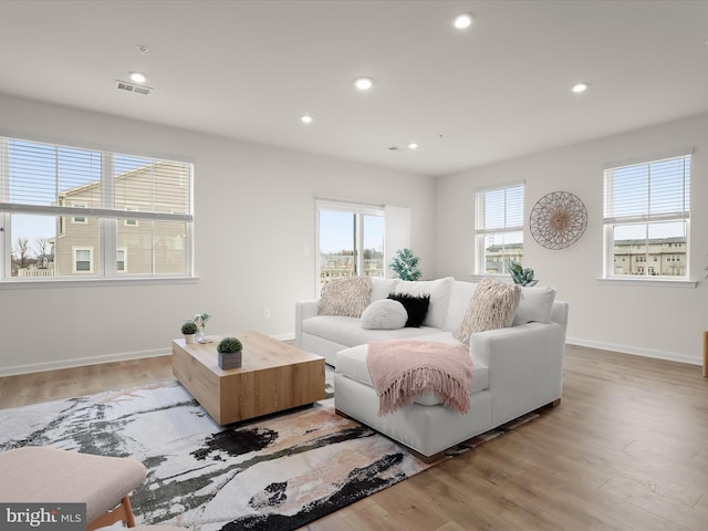 living room with recessed lighting, visible vents, and light wood finished floors