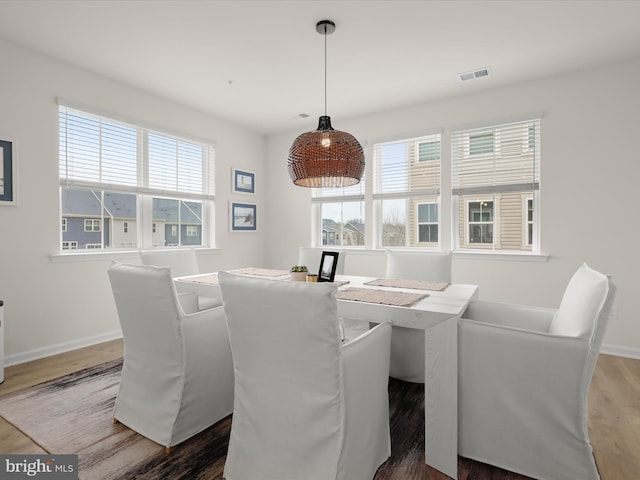 dining room featuring a wealth of natural light, visible vents, baseboards, and wood finished floors