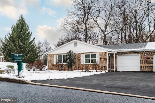 single story home with a garage, brick siding, and aphalt driveway