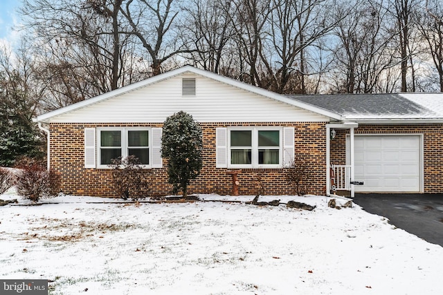 single story home with driveway, brick siding, and an attached garage