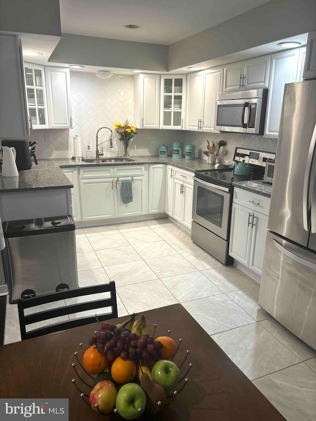 kitchen featuring sink, stainless steel appliances, white cabinetry, and backsplash