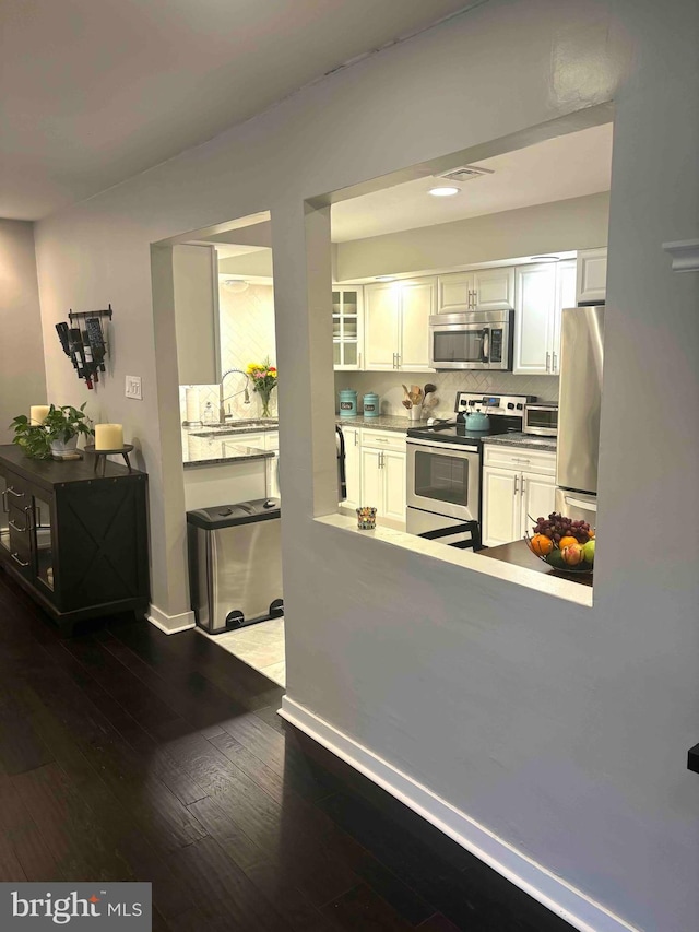 kitchen featuring sink, white cabinetry, tasteful backsplash, dark hardwood / wood-style flooring, and appliances with stainless steel finishes