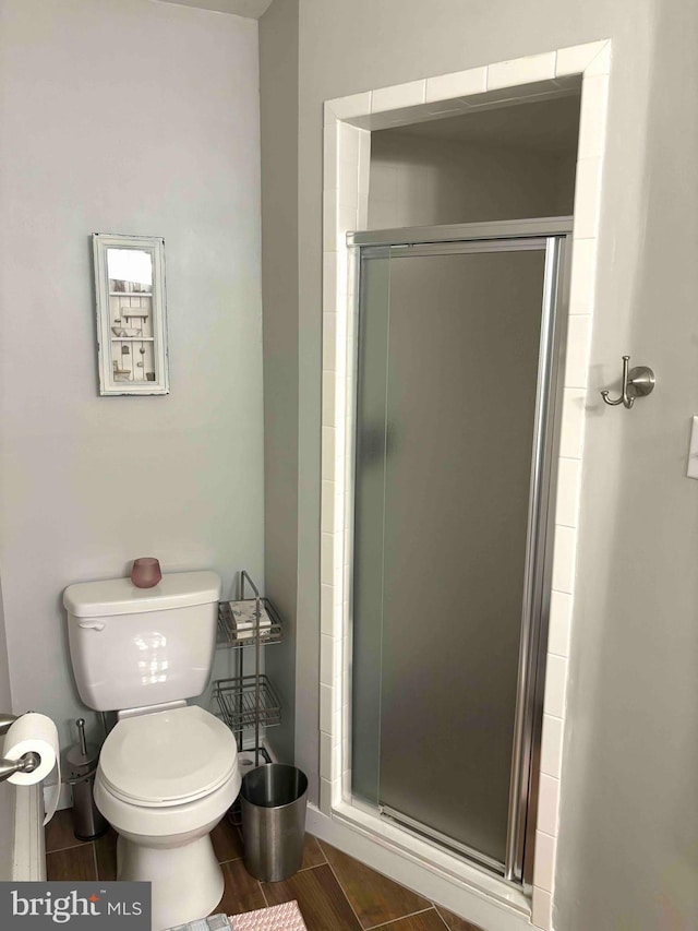 bathroom with toilet and an enclosed shower