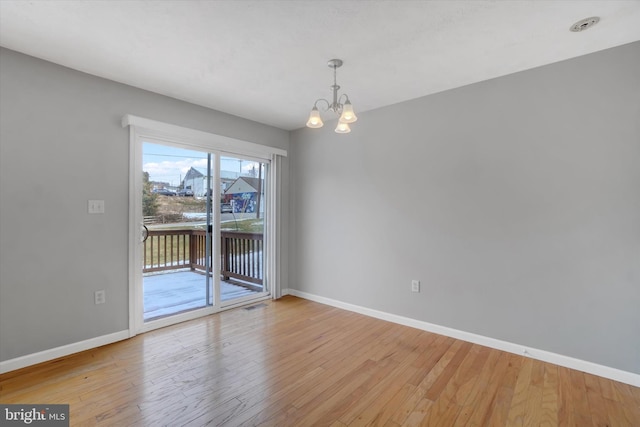 unfurnished room featuring light hardwood / wood-style floors and a chandelier