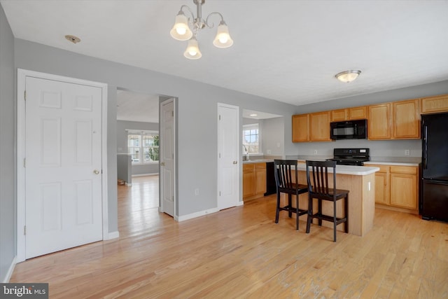 kitchen with hanging light fixtures, an inviting chandelier, a breakfast bar area, a kitchen island, and black appliances