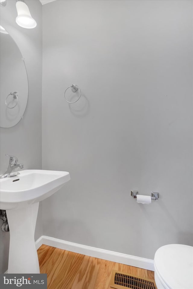 bathroom featuring toilet, wood-type flooring, and sink