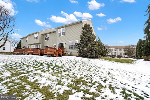 snow covered house featuring a wooden deck