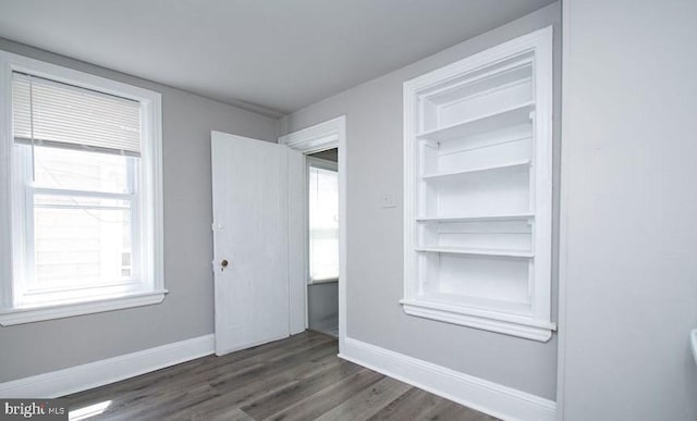 empty room with a wealth of natural light and dark hardwood / wood-style flooring