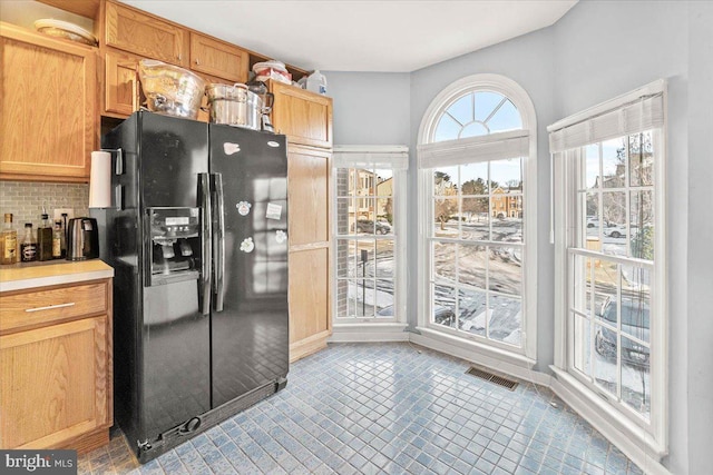 kitchen with light tile patterned floors, black fridge, and decorative backsplash