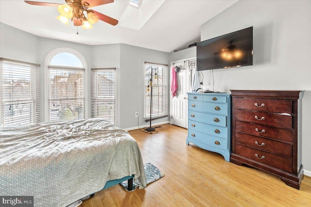 bedroom with light hardwood / wood-style flooring, ceiling fan, and lofted ceiling with skylight