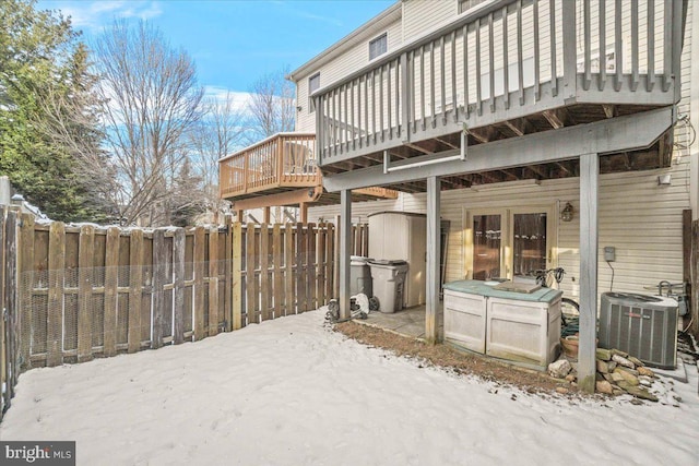 snow covered house with central AC unit and a wooden deck