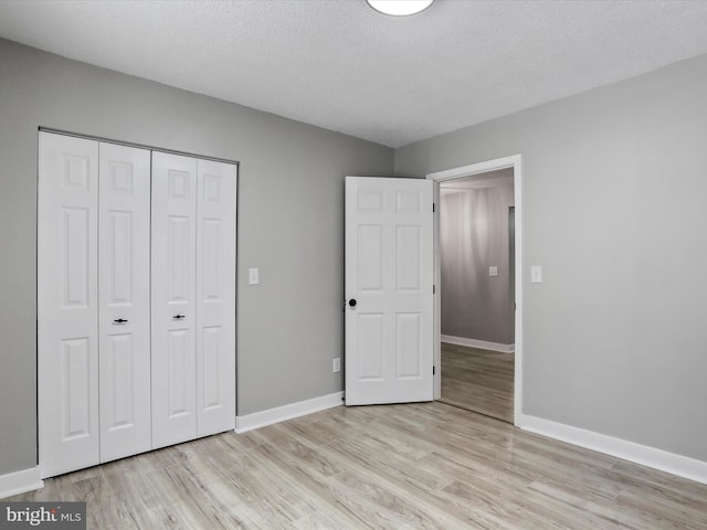 unfurnished bedroom featuring a textured ceiling, a closet, and light hardwood / wood-style flooring