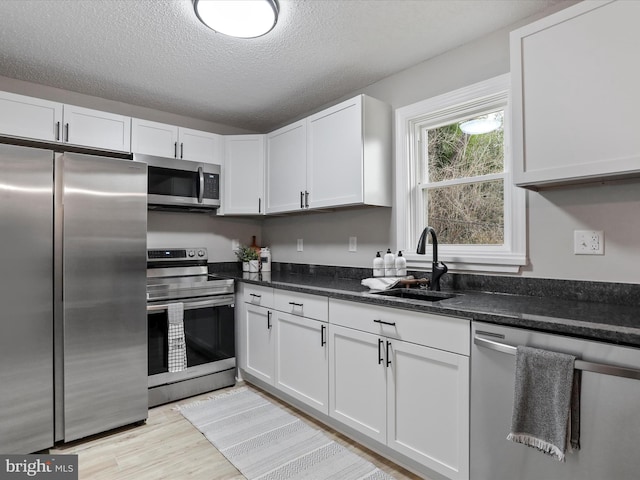 kitchen featuring sink, white cabinets, appliances with stainless steel finishes, and a textured ceiling