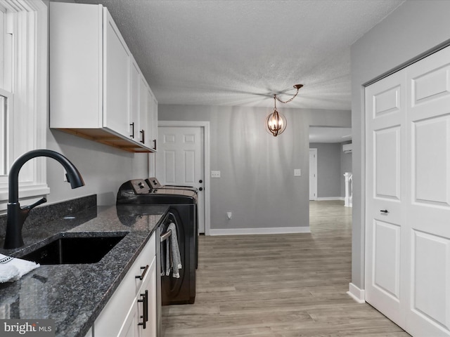 kitchen with separate washer and dryer, white cabinetry, sink, hanging light fixtures, and a chandelier