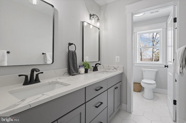 bathroom with toilet, vanity, and tile patterned flooring