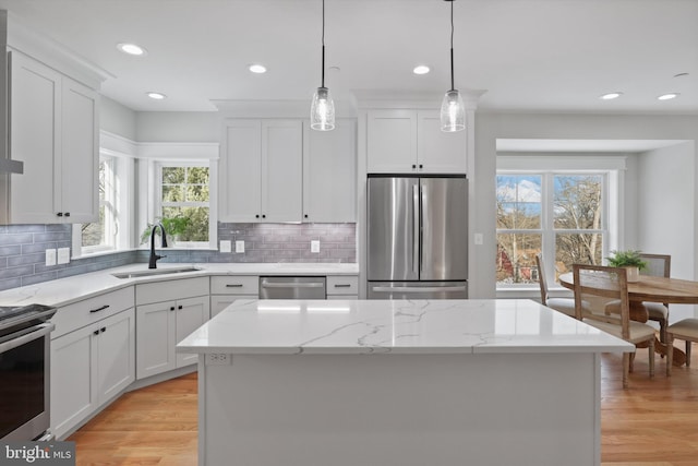 kitchen featuring pendant lighting, a kitchen island, sink, appliances with stainless steel finishes, and white cabinets