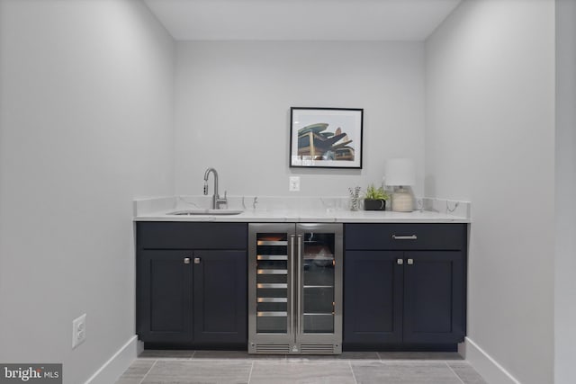 bar with wine cooler, light tile patterned floors, light stone countertops, and sink