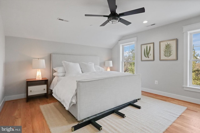 bedroom with ceiling fan, vaulted ceiling, light wood-type flooring, and multiple windows