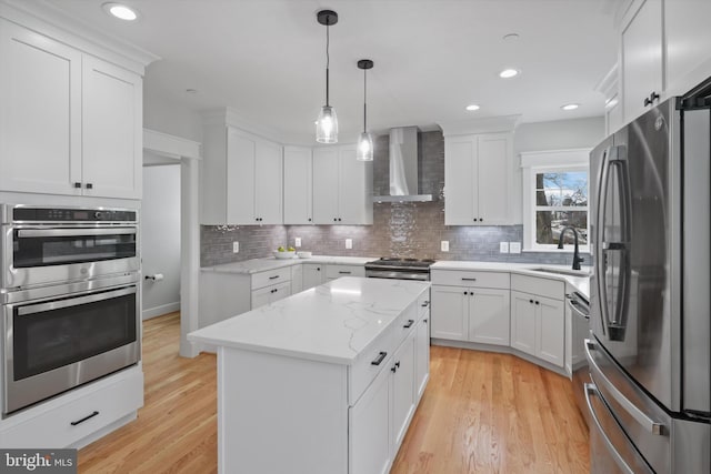 kitchen with appliances with stainless steel finishes, wall chimney range hood, white cabinetry, and a center island