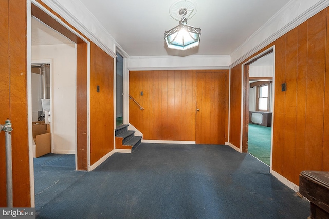 entryway featuring ornamental molding, dark colored carpet, and wooden walls