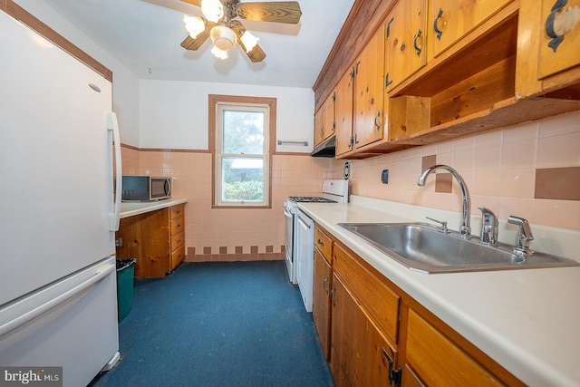 kitchen with white appliances, ceiling fan, tile walls, and sink