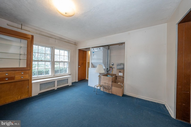 unfurnished office featuring a textured ceiling, stacked washer and dryer, dark carpet, and radiator