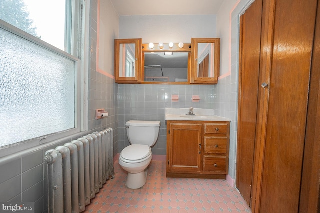 bathroom featuring toilet, tile patterned flooring, tile walls, radiator heating unit, and vanity