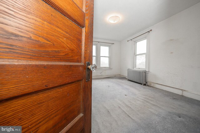 carpeted spare room featuring radiator heating unit