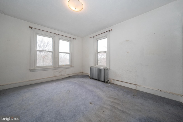 spare room featuring lofted ceiling, radiator heating unit, and carpet