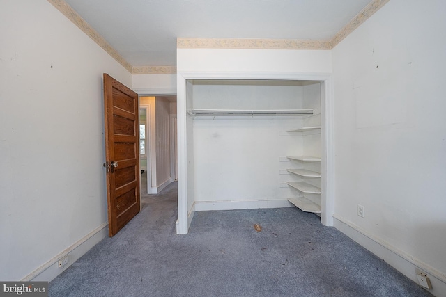 unfurnished bedroom featuring dark carpet and a closet