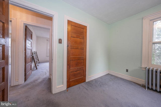 spare room featuring radiator and light carpet